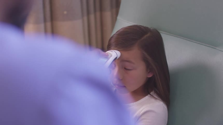 Little girl having her temperature read by a nurse in a clinic