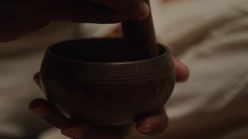 Hand holding and playing a tibetan singing bowl