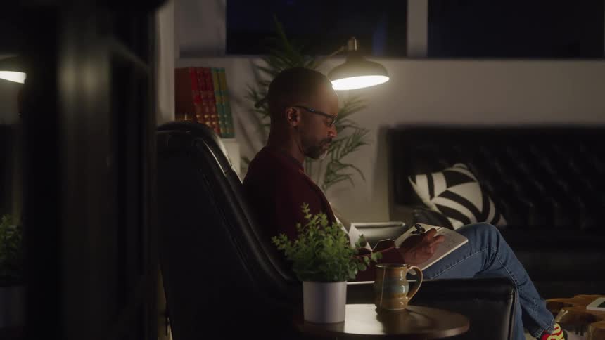 Man sitting in an armchair writing in a notebook