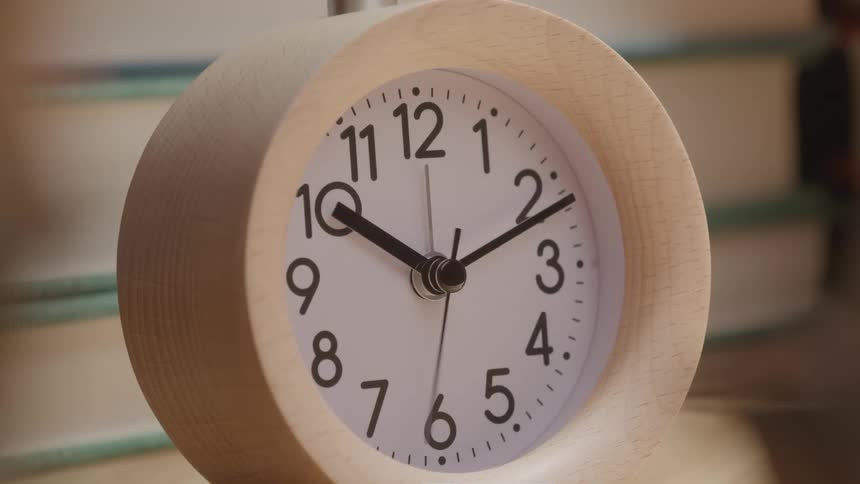Time lapse second hand sweeping around face of round wood framed analog clock