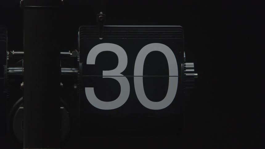 A retrostyle mechanical flip clock flips through numbers quickly counting down from 59 to 0 the large white numbers contrast sharply against the black background creating a bold graphic effect