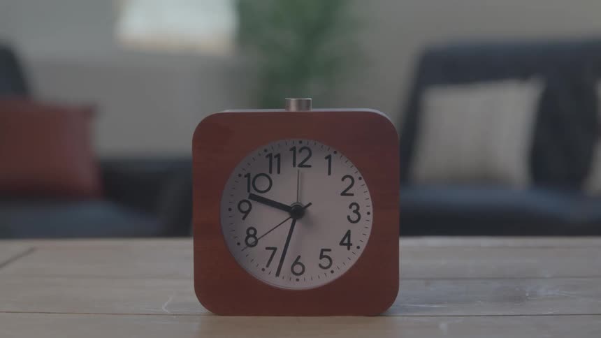 A stopwatch spins continuously on a wooden surface