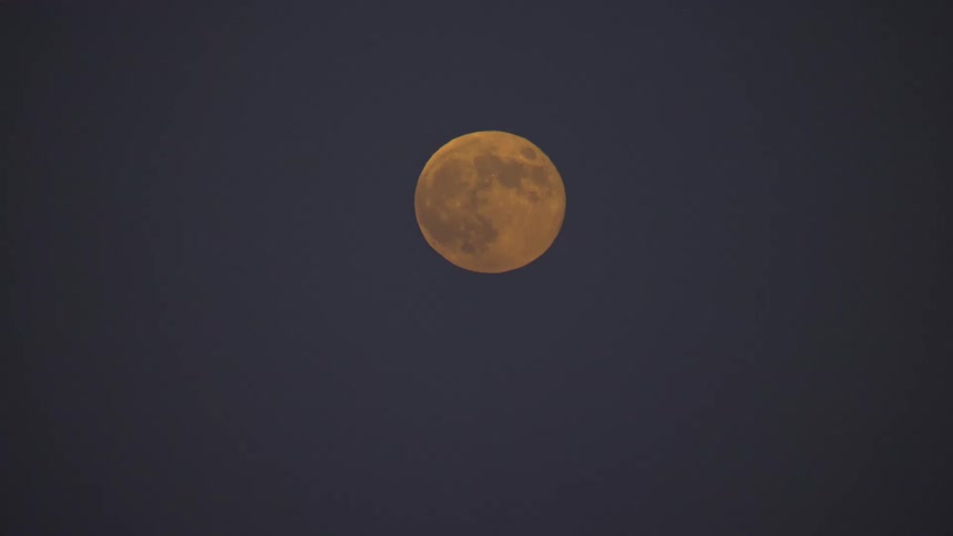 Full moon with crater structure shines alone in the dark night sky