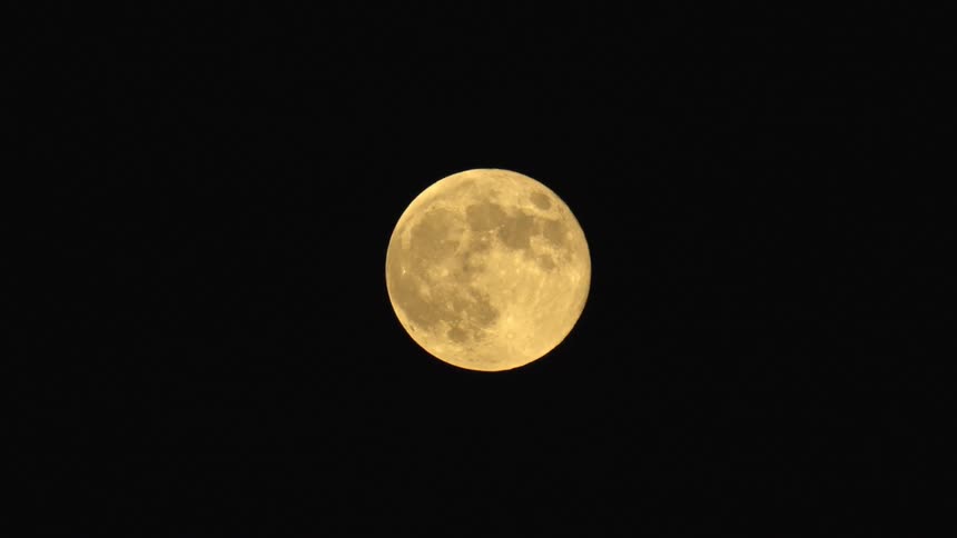 Full moon with crater structure shines alone in the dark night sky