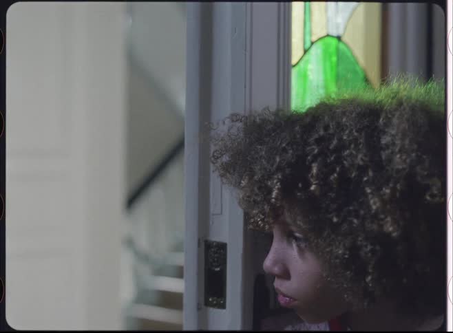 Close up portrait of a male teenager peeping through a door in a building during daytime