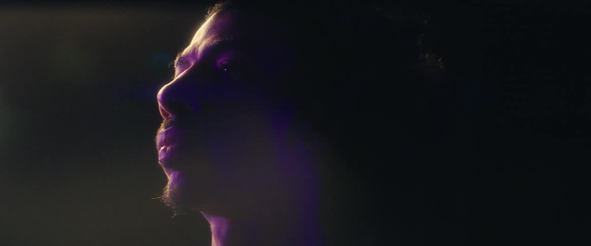 A young man stands on a stage at night