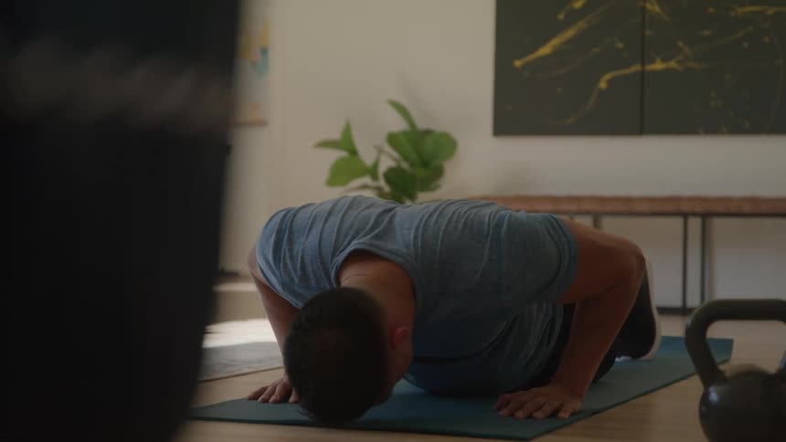 A young man does push ups indoors during daytime