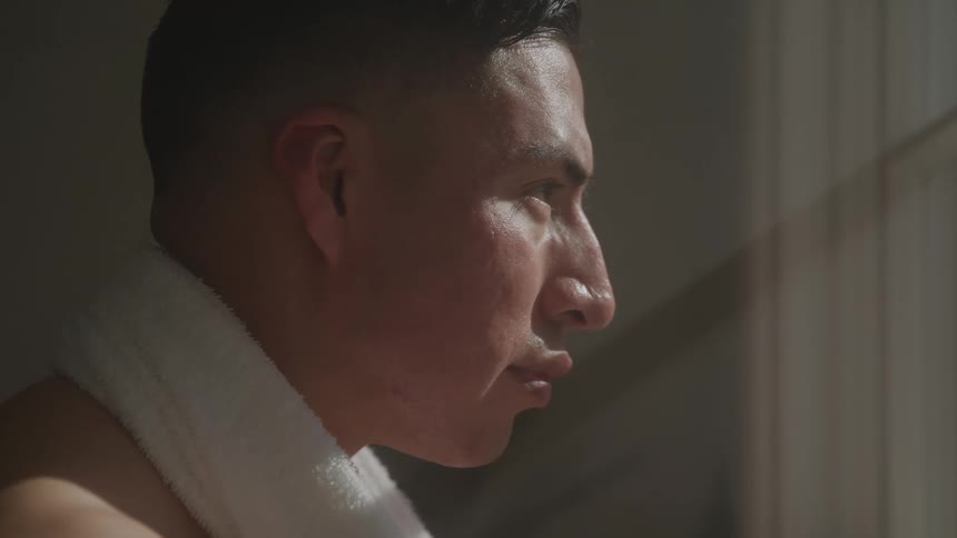 Man with a towel around his neck looking out the window