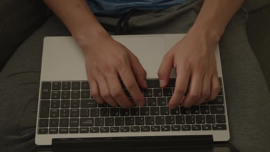 A man is typing on a laptop