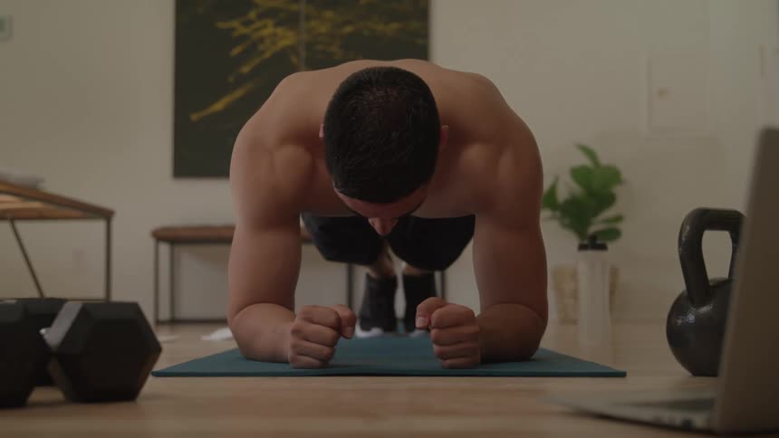 Man doing a plank on a mat without a shirt