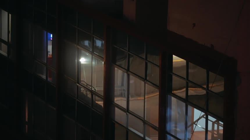 Glass facade of a building reflecting indoor and outdoor lights at night