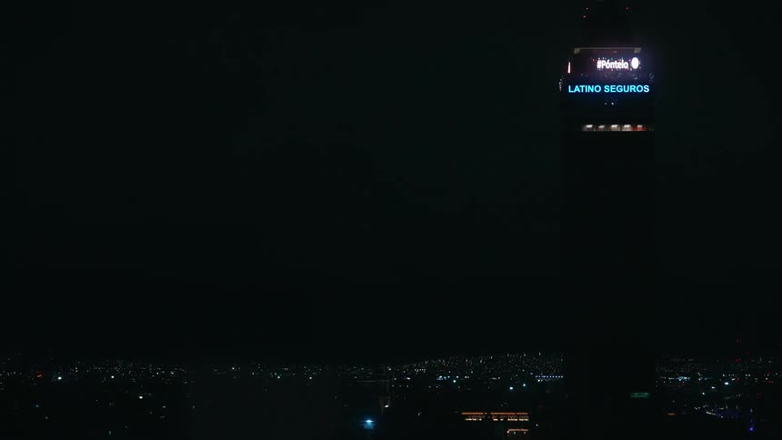 Metropolitan city skyline at night with a tower building displaying the time