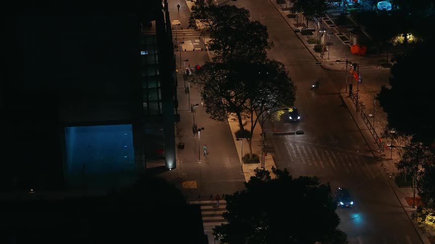 Aerial of a busy sidewalk and street in a metropolitan city at night