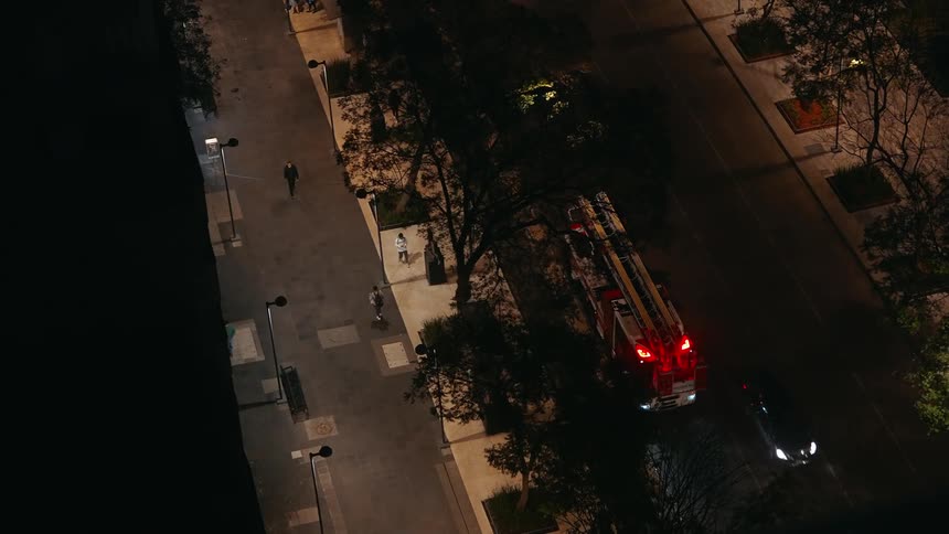 Fire truck and police cars parked on a lit street at night