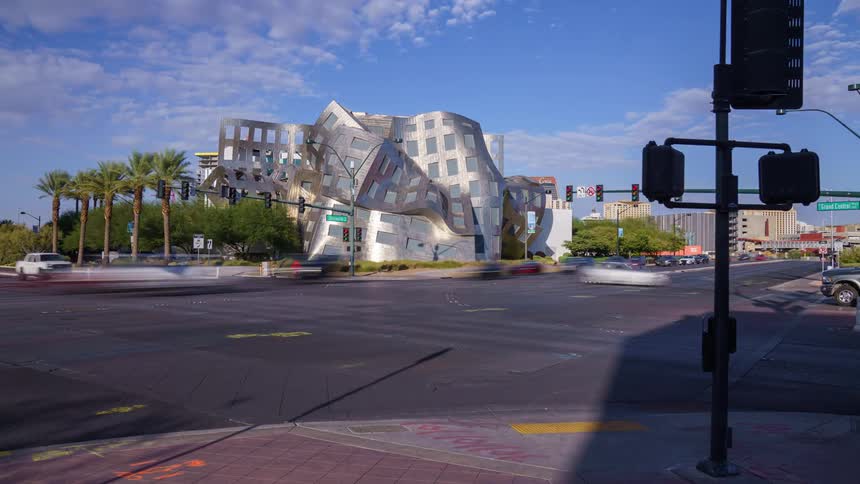 Wavy metallic architectural building in the background of a busy intersection with pedestrians and cars in Las Vegas