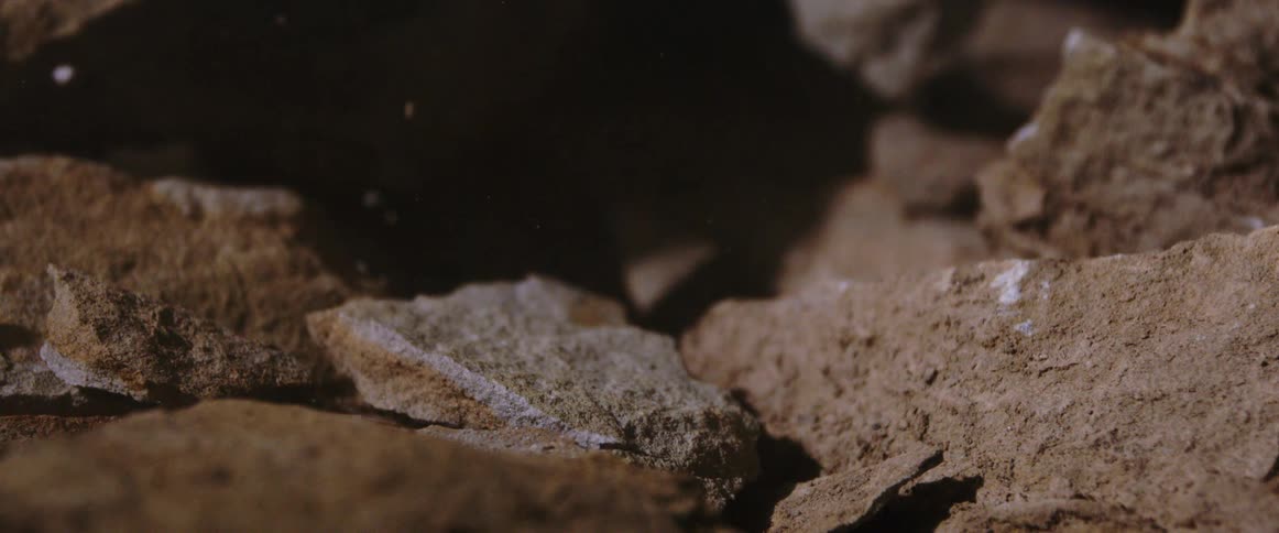 Brown rock fragments breaking with dust particles in the air