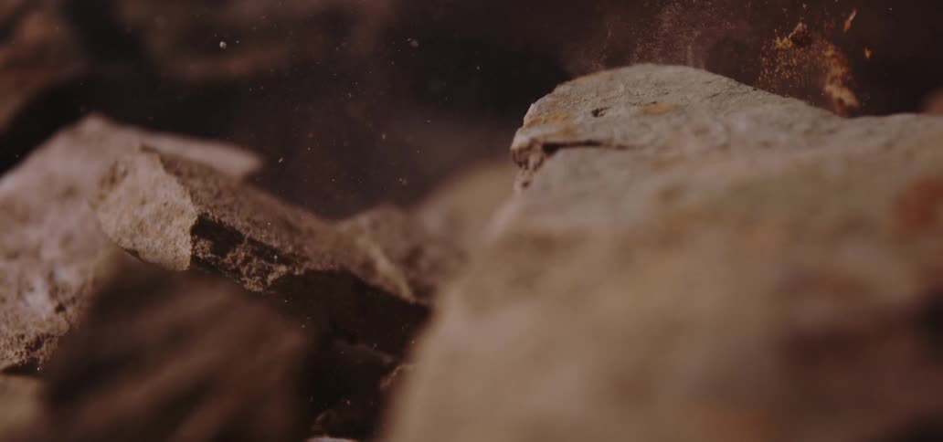 Closeup of brown rocks with dust particles coming off