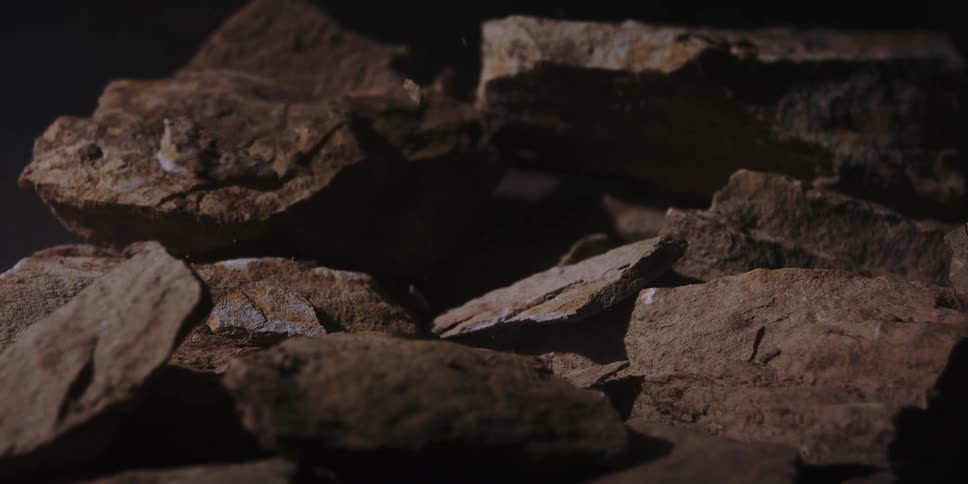 Falling stone hitting rock and shattering it