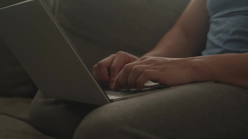Person typing on a laptop resting on their lap
