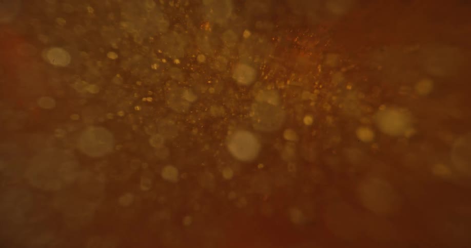 Close up of a golden thick liquid poured through a metal pipe