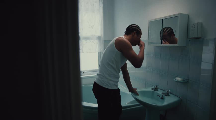 Man rinses his face then faces his reflection in the bathroom mirror