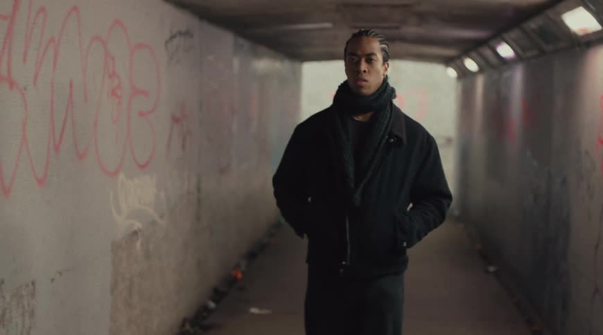 Woman looks back then speeds up while walking through a tunnel leaving a man to frown and walk on his own