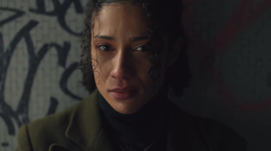 Woman crying in front of a graffitied wall