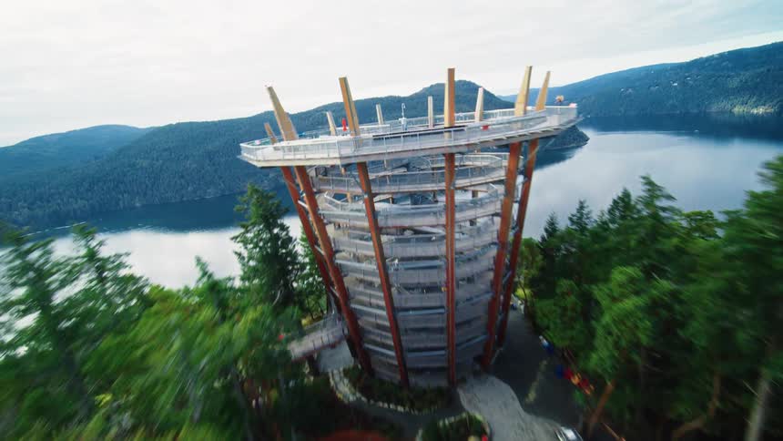 Observation tower surrounded by trees overlooking a lake and mountains