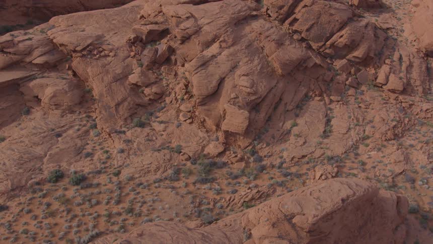 Rugged red rock formations rise sharply in a desert landscape