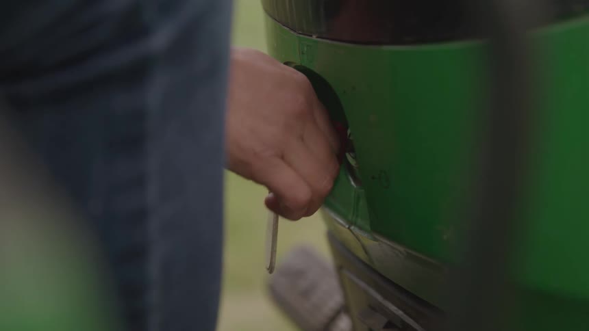 Hand turning the ignition key of a green vehicle