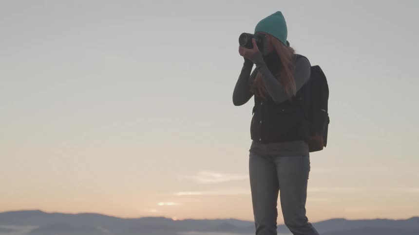 Woman taking photographs outdoors at sunrise