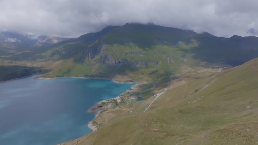 Aerial view of a blue lake surrounded by green mountains and low clouds