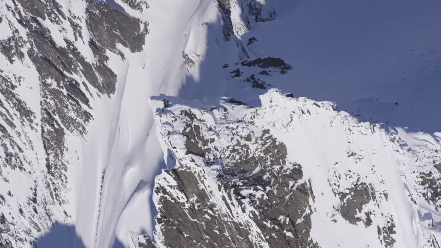 Rock wall covered with snow and shadows cast by the terrain