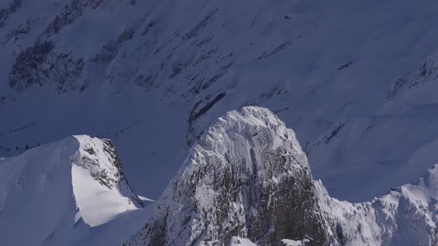 Steep snowcovered mountain peak surrounded by snowy slopes