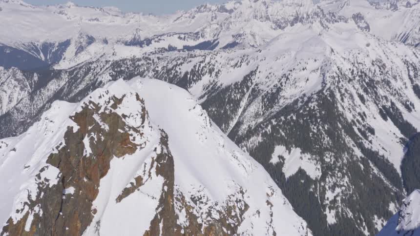 Rocky peak covered with snow with a mountain range in the background