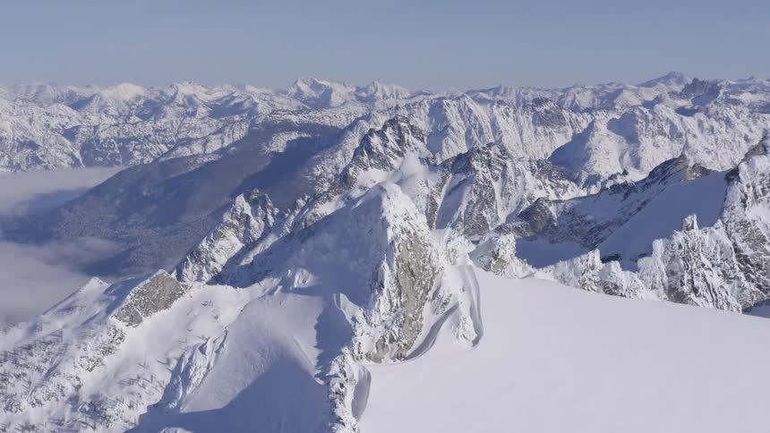 A range of high mountains covered in white snow that stretch to the horizon