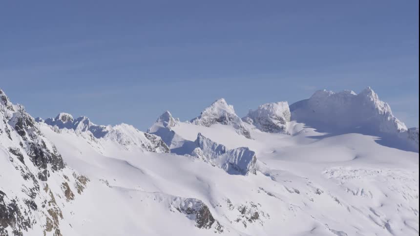 Aerial of summit covered in snow on blue sky background