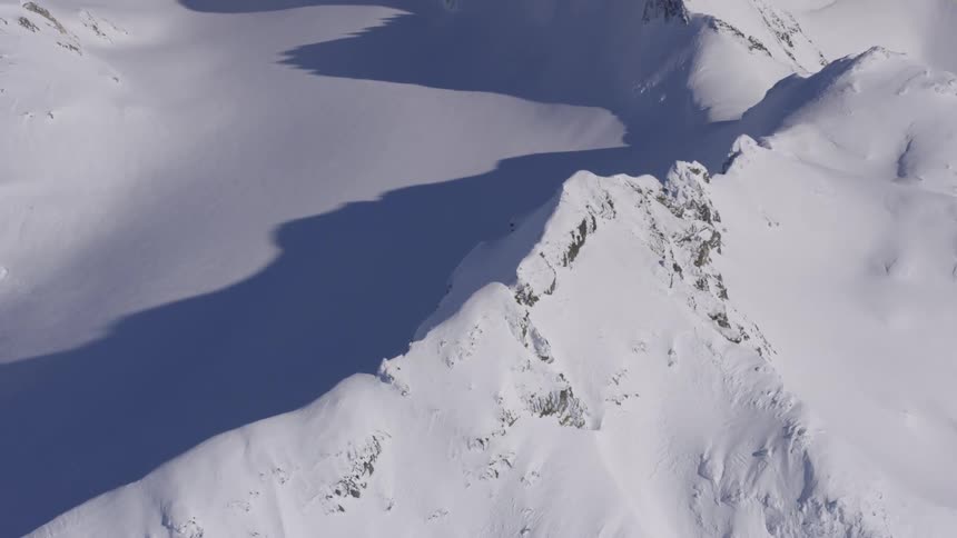 Snowcovered mountain range with shadows cast over the valley