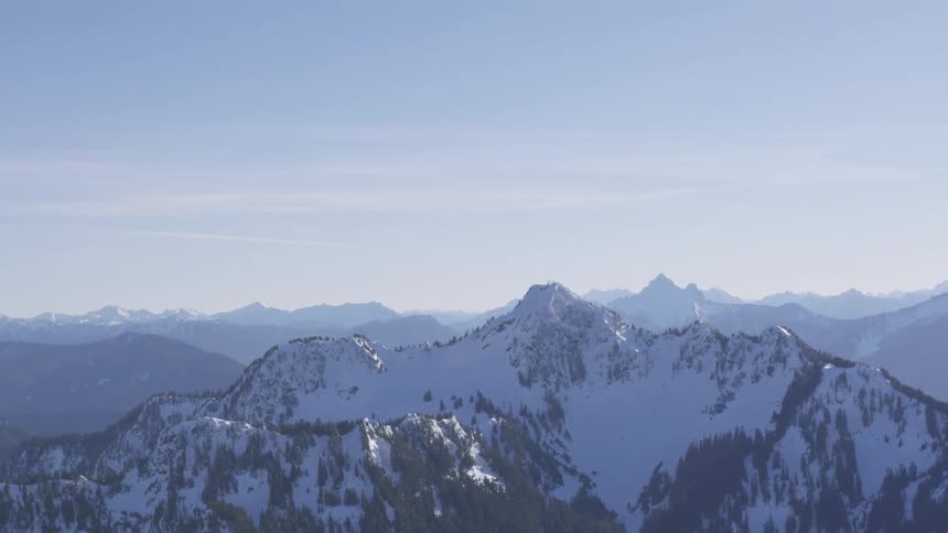 Snowcovered mountain range stretches under clear blue sky