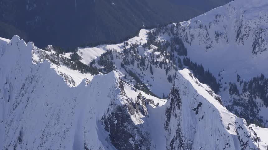 A mountain range with rough terrain covered in snow at midday