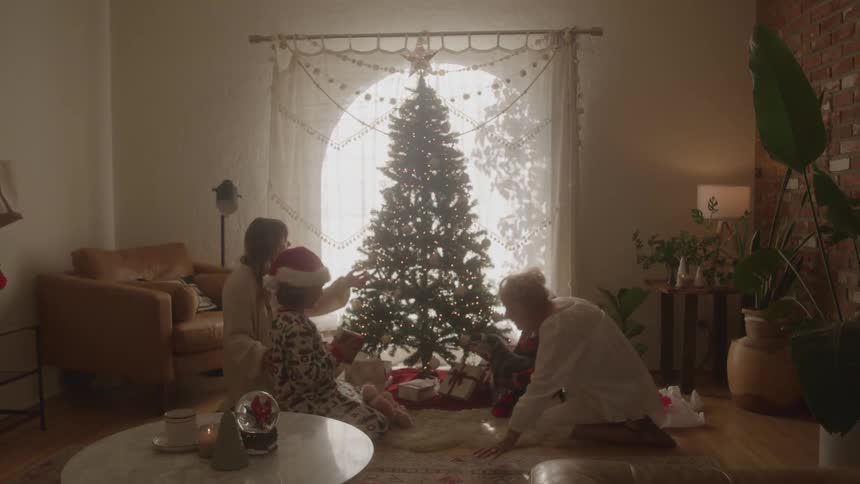 A family gathers around a decorated christmas tree in a cozy living room