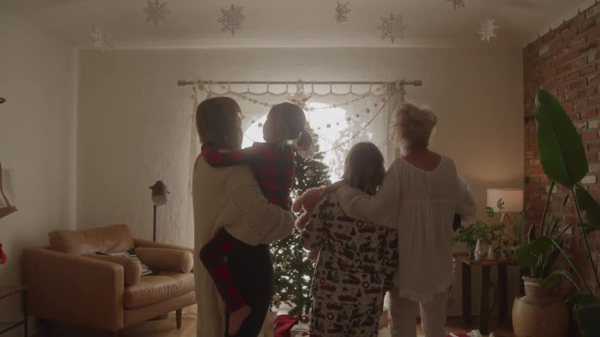 Family in pajamas gathered in the living room in front of a christmas tree