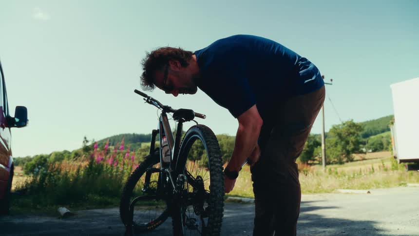 Man inflating a bicycle tire next to a parked van