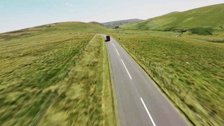 A delivery van drives on the freeway in a rural area at midday