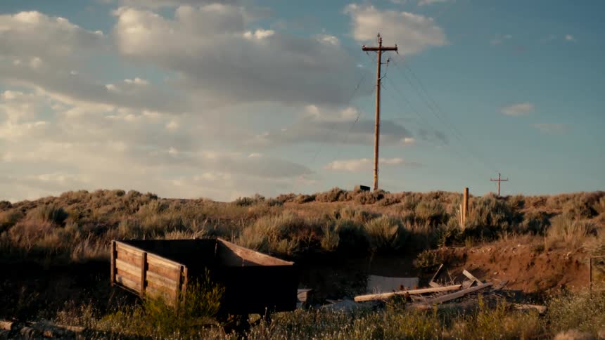 Abandoned wooden trailer in a grassy rural landscape