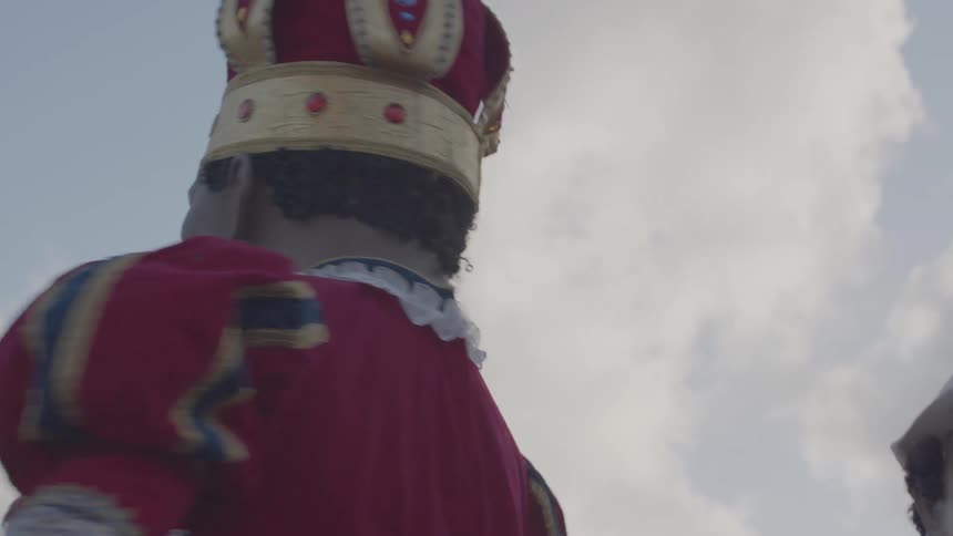 Giant puppets wearing colorful outfits and golden crowns