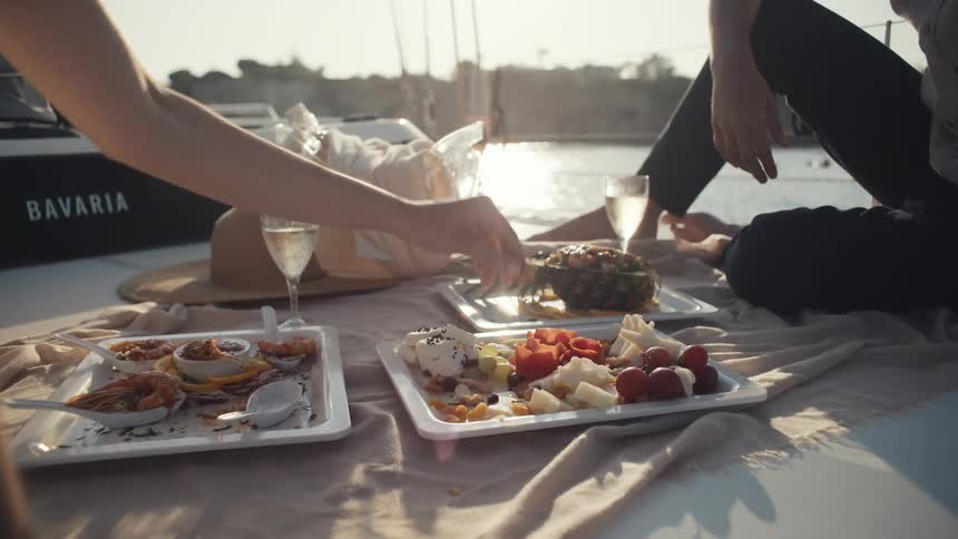 Picnic with seafood fruits and wine on a boat at sunset