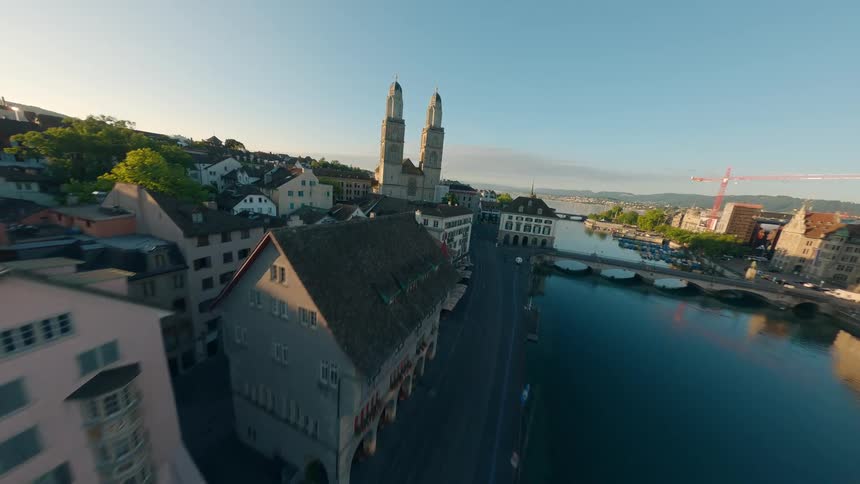An FPV drone flies over the rooftops of zurich following a river that flows into the lake of Zurich