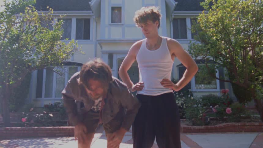 Two men out of breath look at something ahead in a residential yard