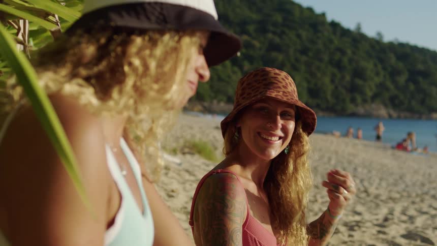 Smiling women chat by the beach under the sun